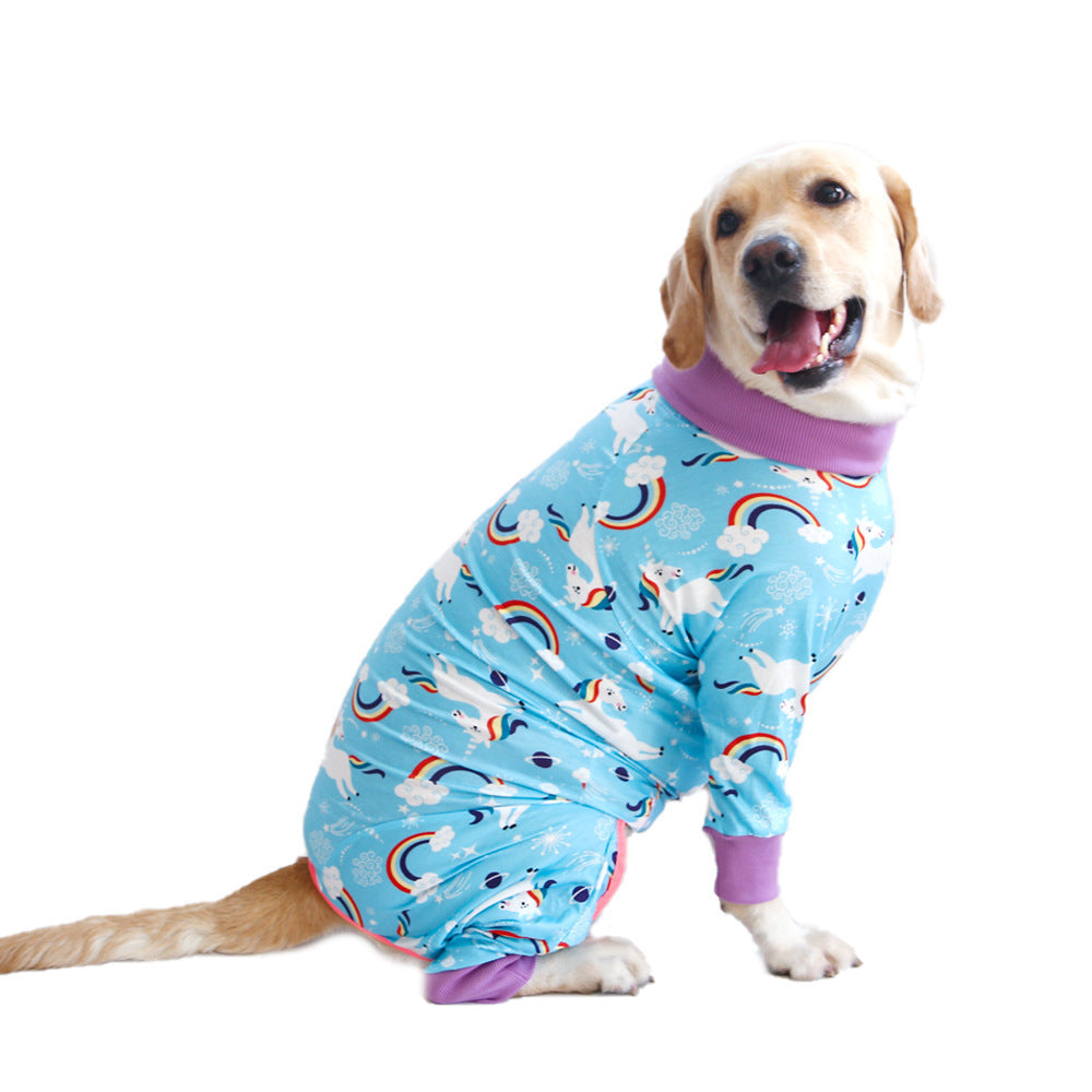 Chien heureux portant un pyjama en coton bleu à motifs mignons de licornes et arc-en-ciel.