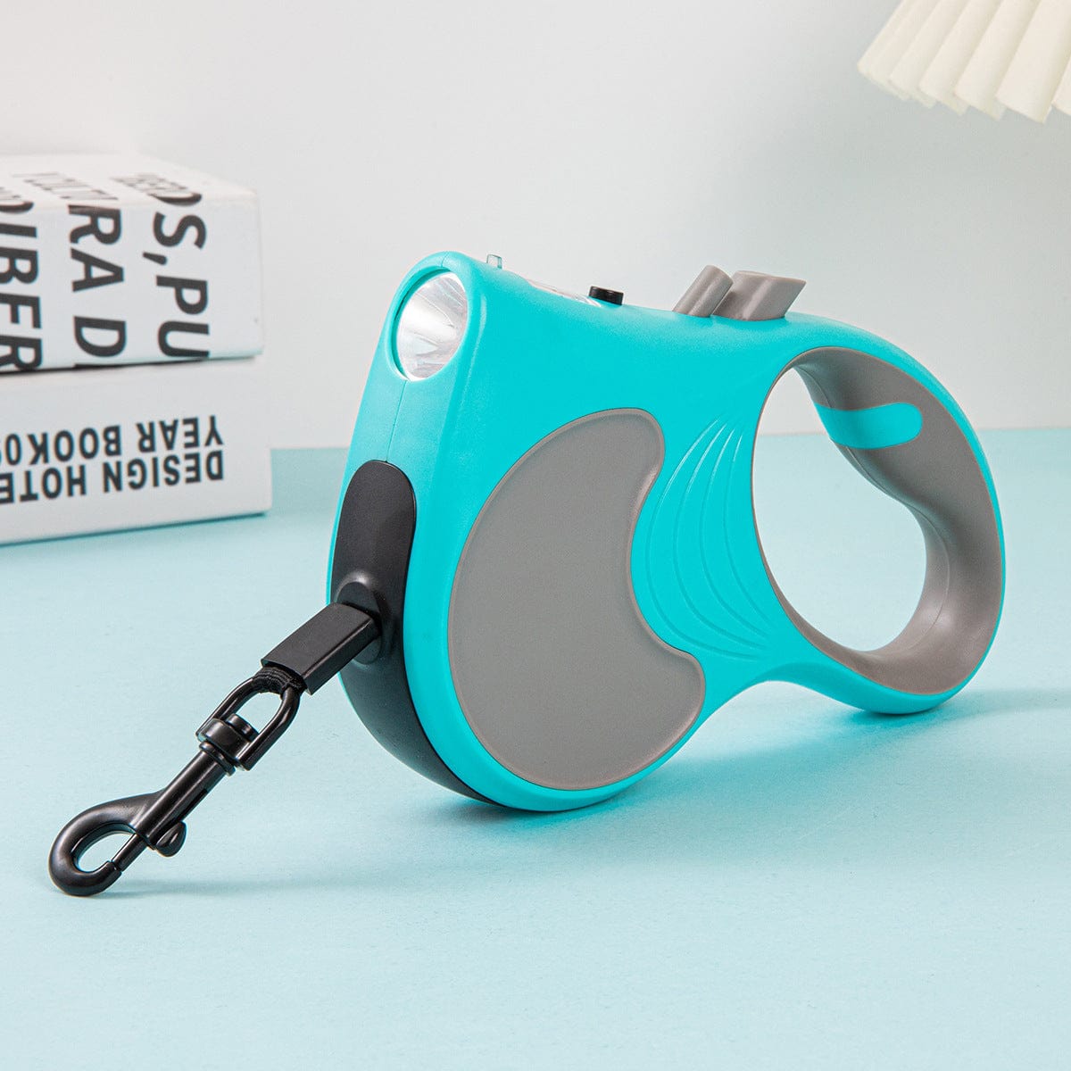 Laisse automatique rétractable pour animaux avec lumière, coloris turquoise et gris, idéale pour les promenades nocturnes.