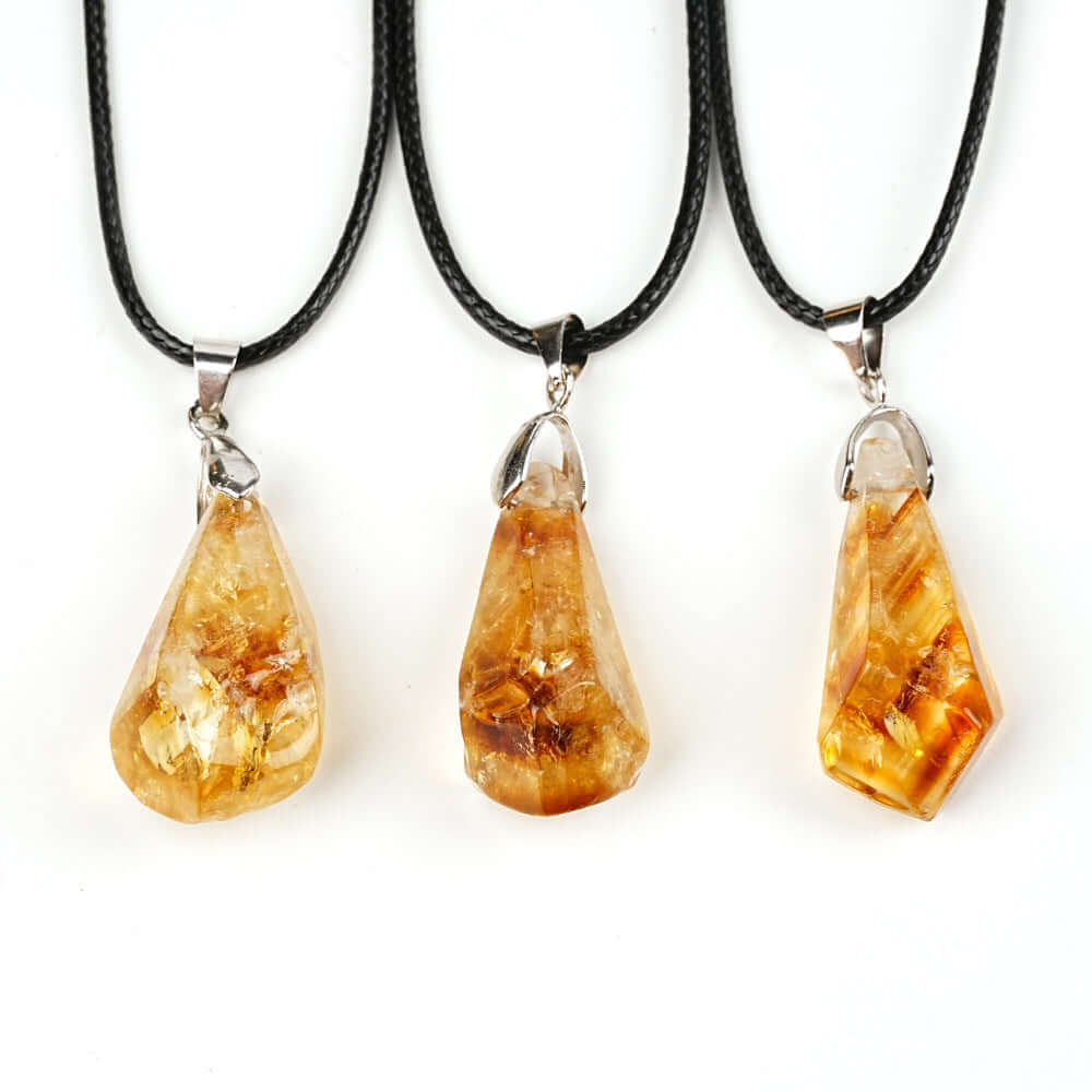 Pendentifs en citrine naturelle, forme irrégulière, suspendus à des cordes en cuir, éclat doré et unique.