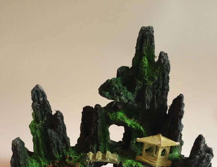 Rocaille en résine synthétique ultra réaliste pour aquarium, imitant les roches naturelles avec un petit pavillon en bois.
