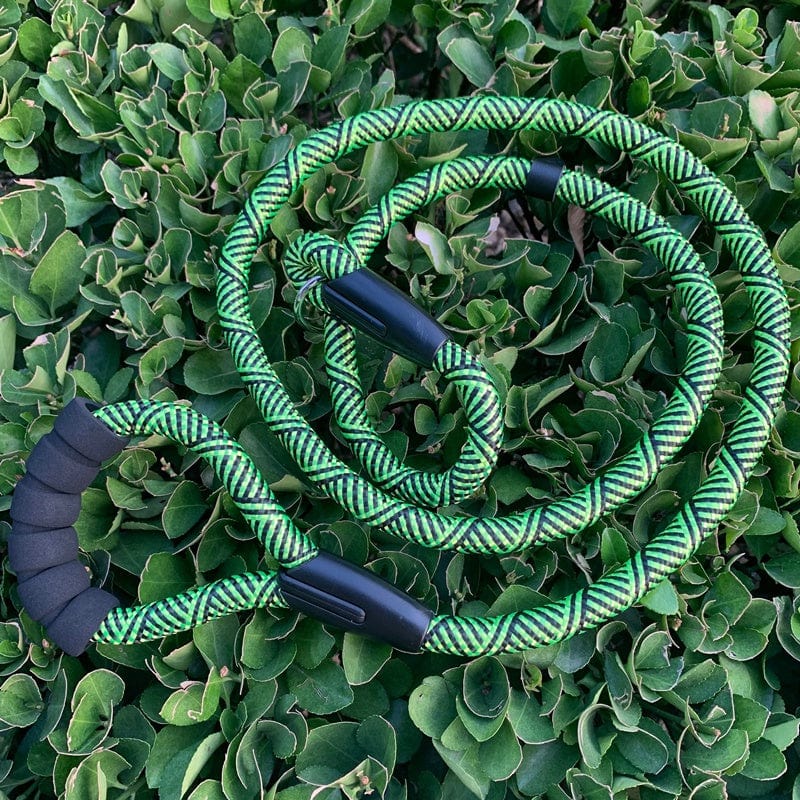 Chaine pour chien en vert avec poignées confortables, adaptée aux chiens de grande taille, sur fond de feuillage.