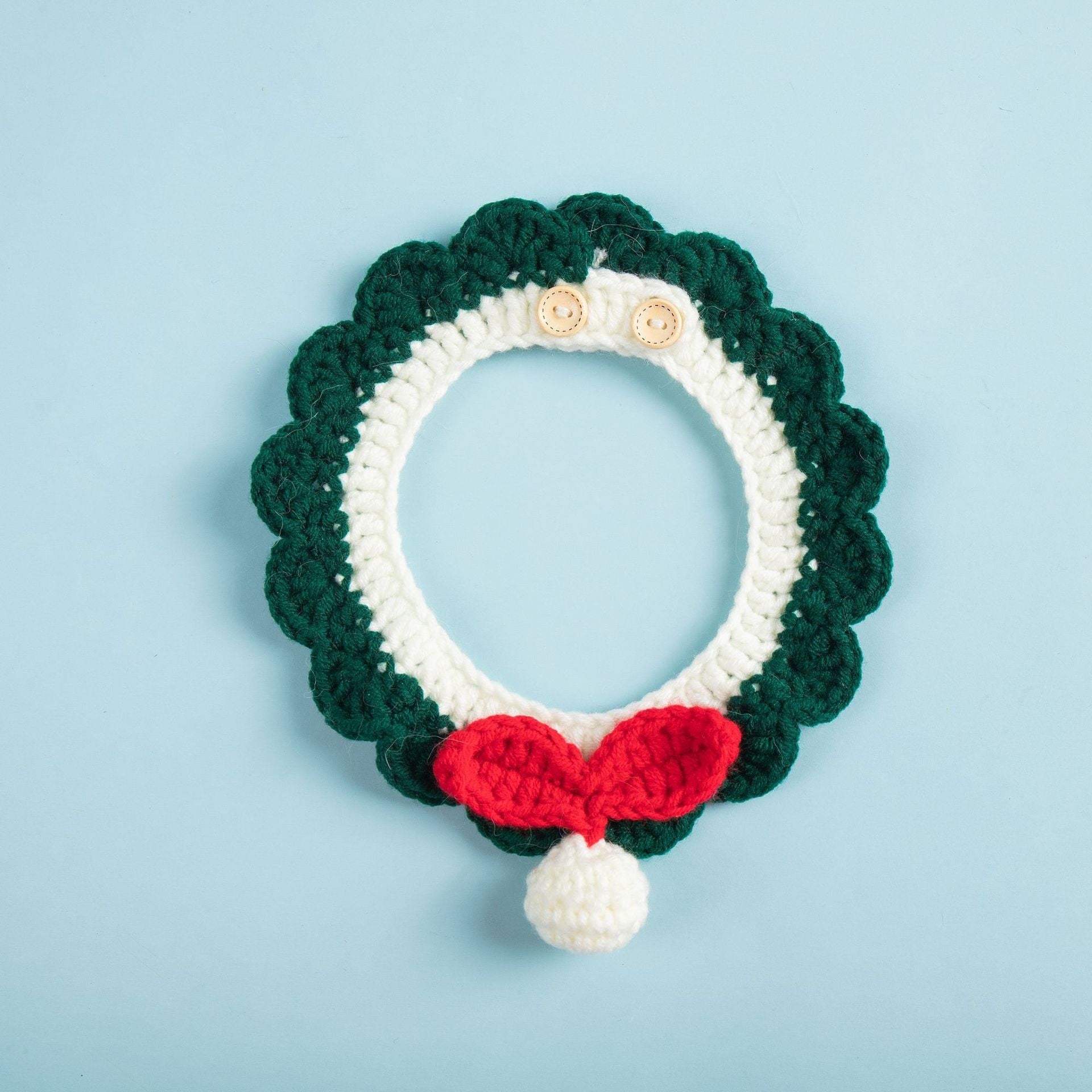 Écharpe tricotée pour chat en vert et blanc, ornée d'un nœud rouge et d'une boule, accessoire stylé pour animaux.