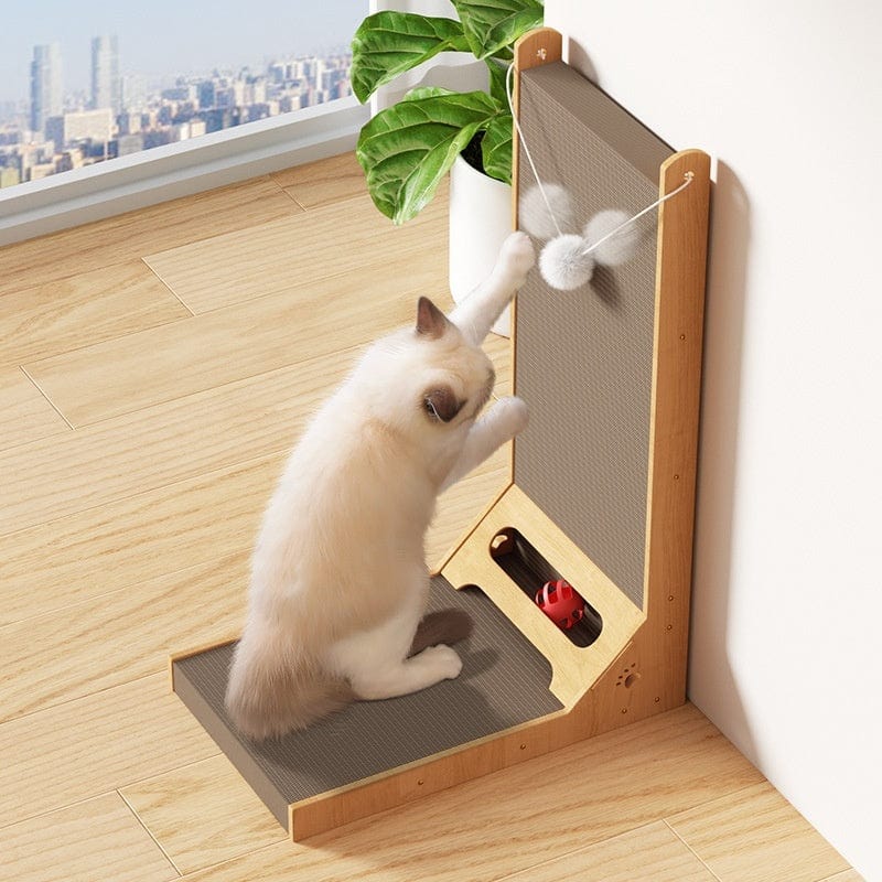 Chat jouant avec un griffoir vertical en carton ondulé près d'une fenêtre, décoré d'un jouet moelleux.