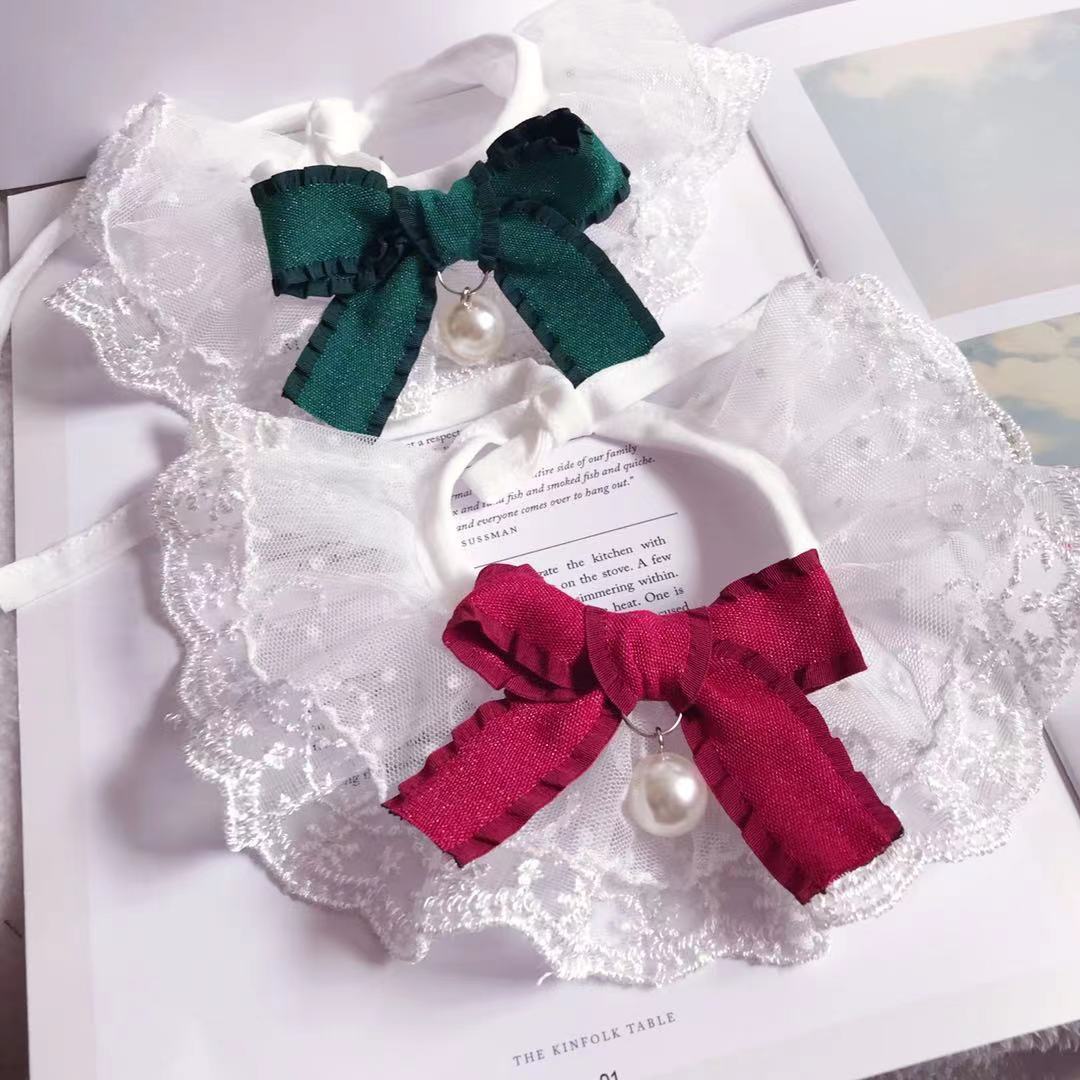 Bavoir en dentelle pour animaux de compagnie avec des nœuds en vert et rouge, élégant et pratique pour chiens et chats.