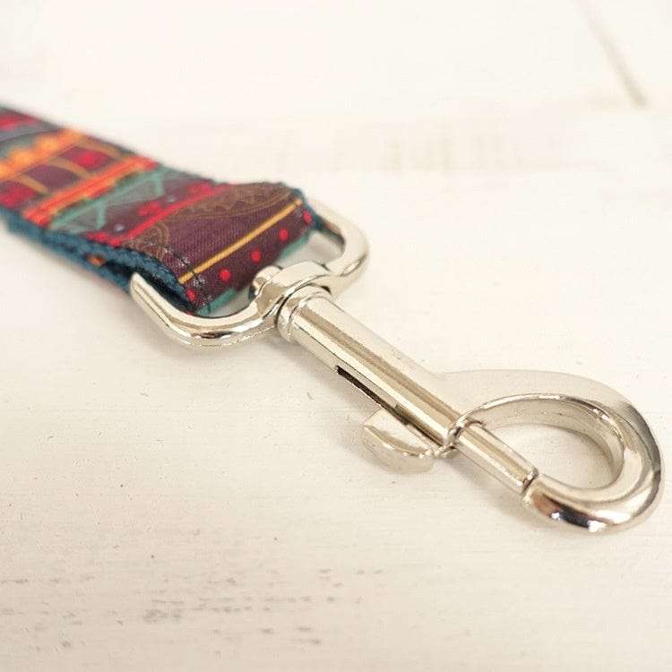 Détail d'une ceinture de traction en tissu à motif individuel avec un clip en métal brillant.