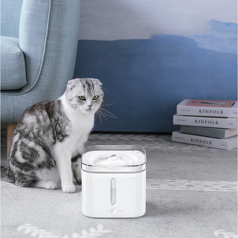Fontaine à boire pour animaux blancs à côté d'un chat dans un salon moderne.