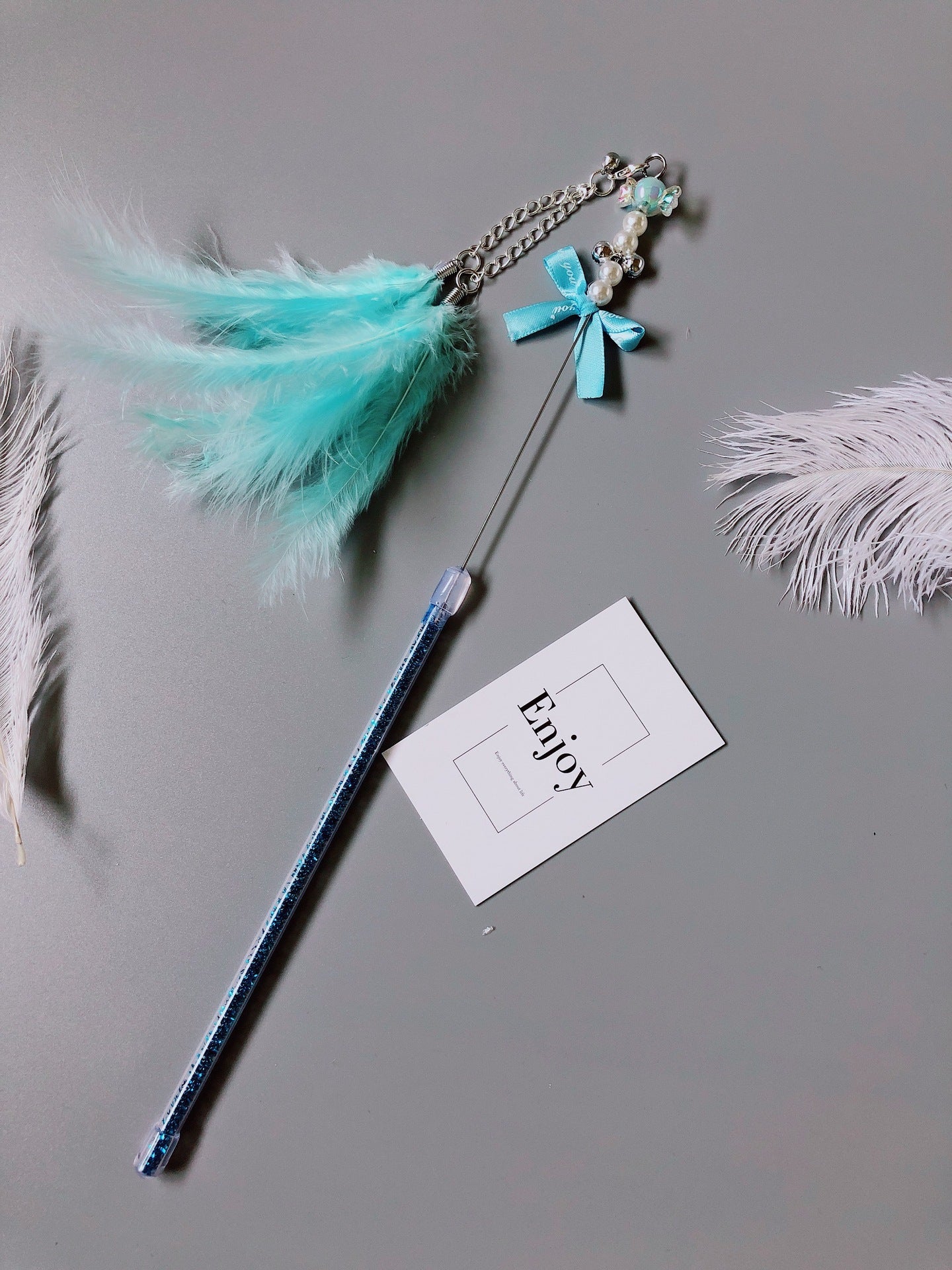 Bâton à lancer fait main pour chat en cuir, avec plumes et décorations, conçu pour un jeu interactif.