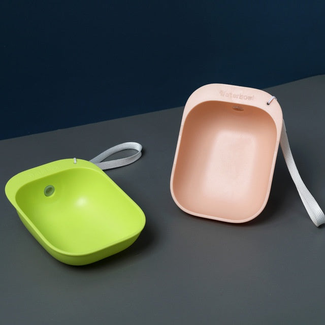 Bol à boire portable pour animaux, en plastique vert et rose, avec lanière pour un transport facile.