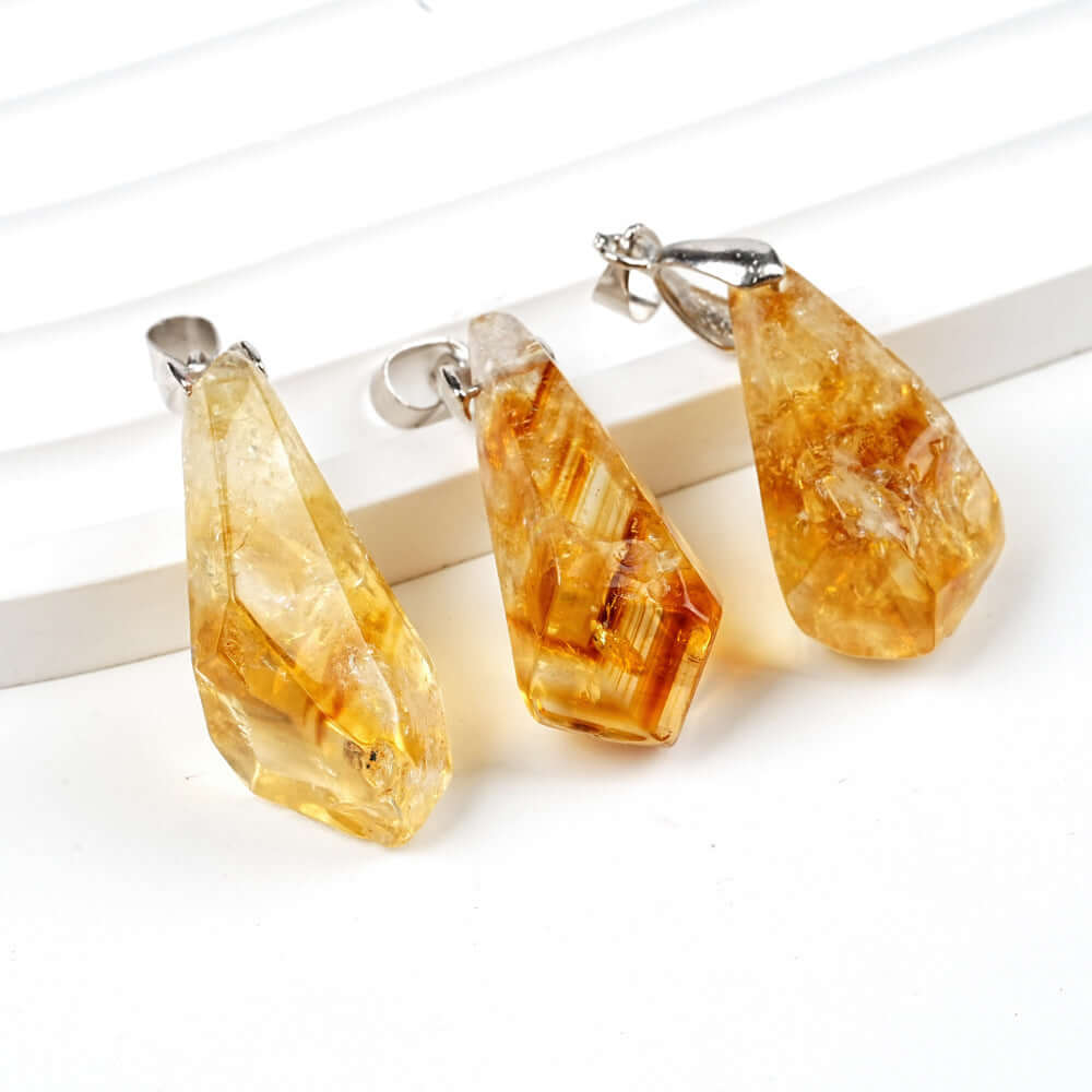 Pendentif cluster en citrine naturelle, formes géométriques irrégulières, éclat doré, suspendu à un fermoir argenté.