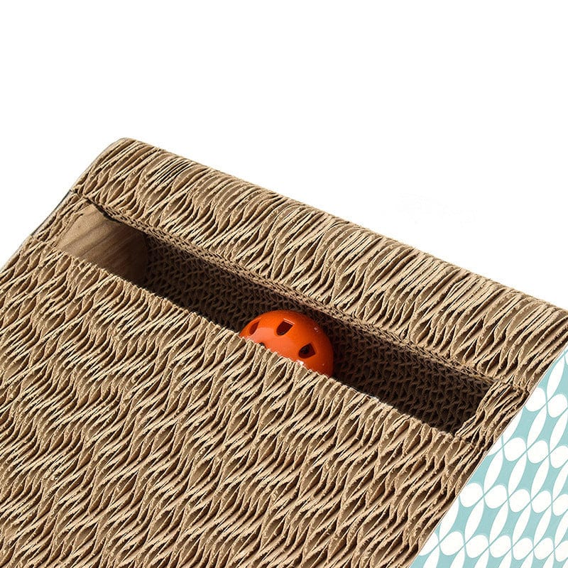 Planche à gratter en carton pour chats avec balle orange qui dépasse, matériau durable et écologique.