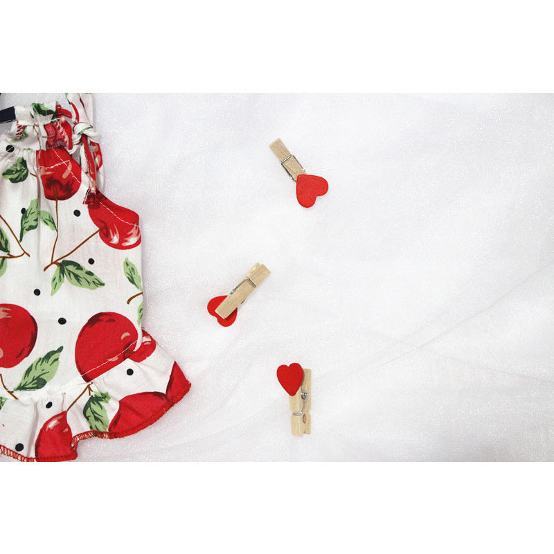 Robe d'été pour animaux en tissu léger à motifs de cerises, accompagnée de pinces en cœur sur fond blanc.