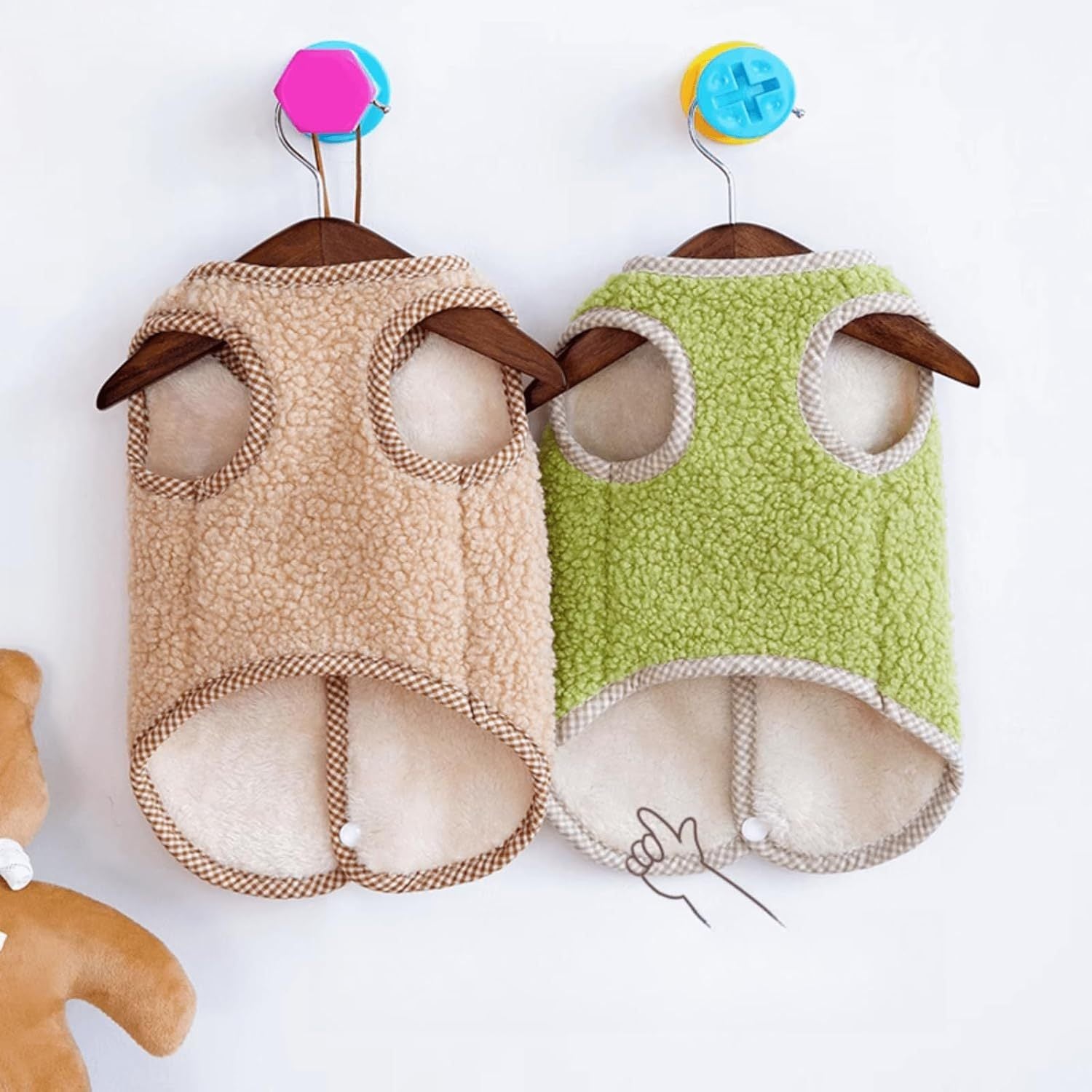 Gilet en polaire pour chien, coloris beige et vert, suspendus sur un cintre, idéal pour l'automne et l'hiver.