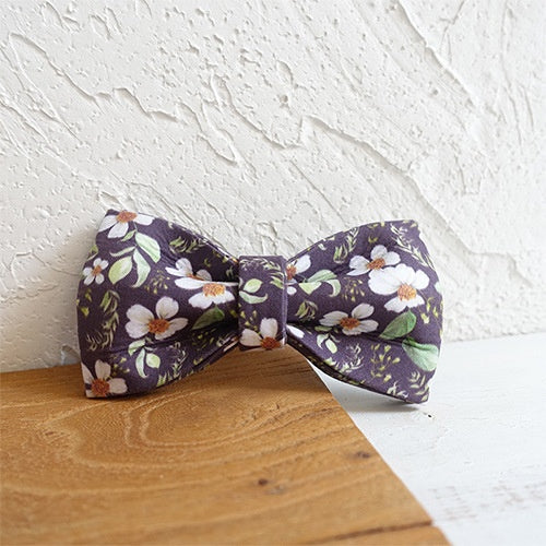 Noeud papillon en tissu floral sur fond en bois, parfait pour des occasions spéciales et un style élégant.