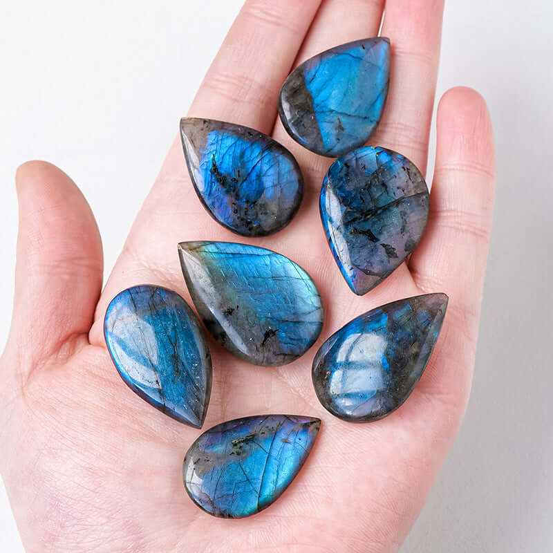 Gouttes en labradorite naturelle aux reflets bleus, présentées dans une main.