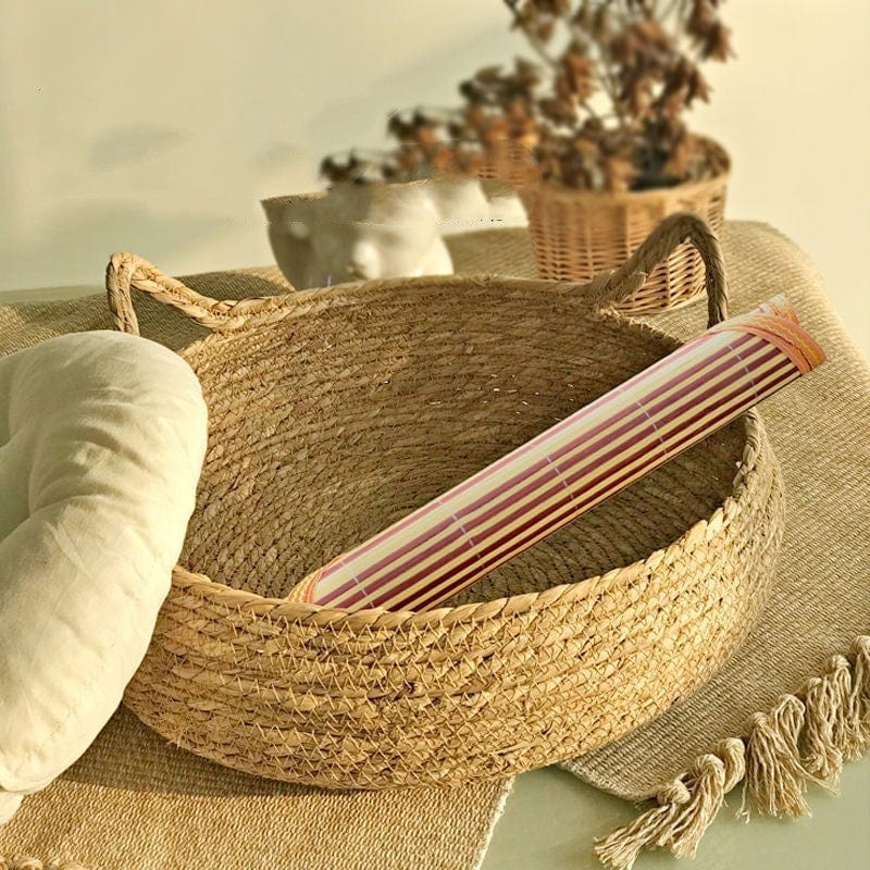 Panier en rattan naturel avec un coussin et un accessoire décoratif à rayures, parfait pour animaux.