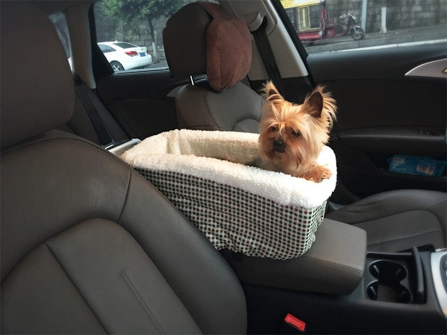 Sac de voiture pour animaux avec un petit chien assis confortablement à l'intérieur, installé sur le siège avant d'une voiture.