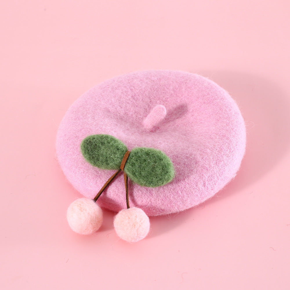 Chapeau en laine rose pour chat avec décoration cerise en feutre, parfait pour ajouter du style à la garde-robe de votre animal.