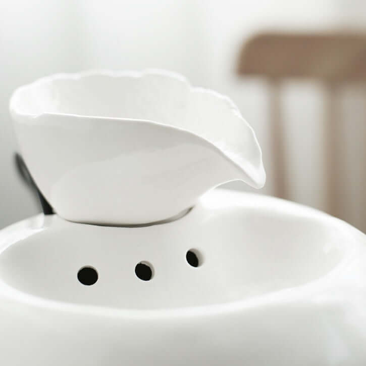 Distributeur d'eau automatique pour chat en porcelaine blanc, design élégant avec un bec et des trous d'écoulement.