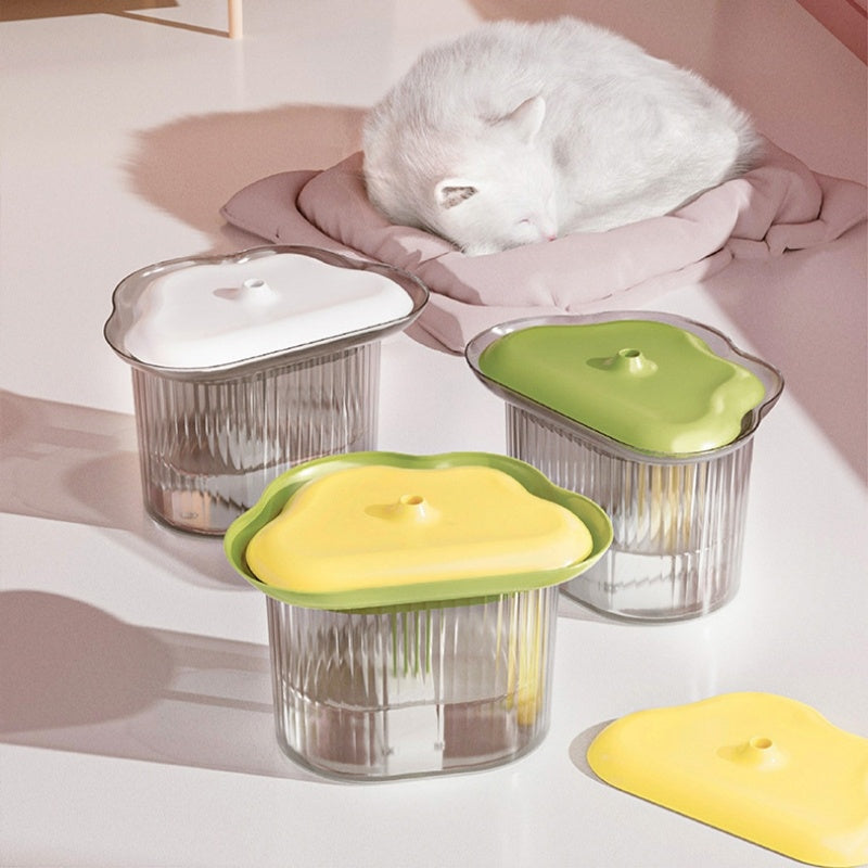 Trois contenants de rangement colorés pour animaux avec un chat blanc dormant à côté.