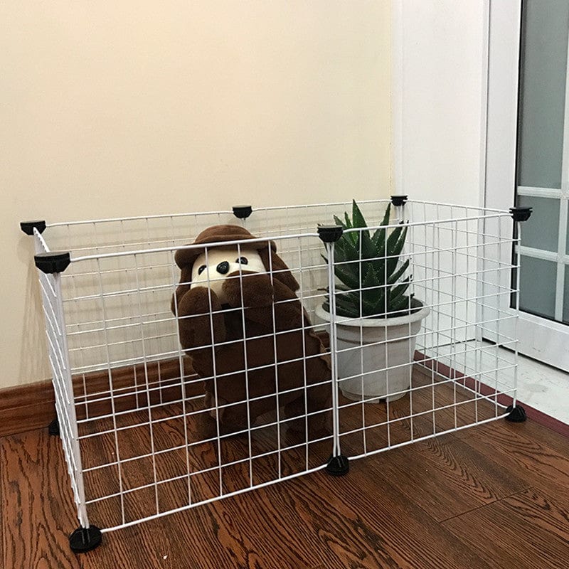 Cage isolante pour animaux avec ours en peluche à l'intérieur et plante à côté, conçue pour le confort et la sécurité des animaux.