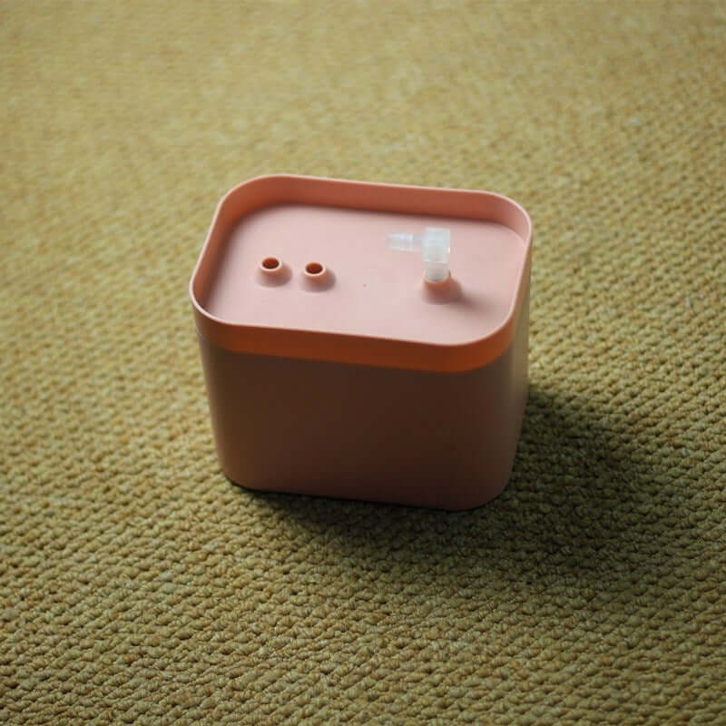 Distributeur automatique d'eau circulant pour animaux, en matériau rose, sur un tapis.