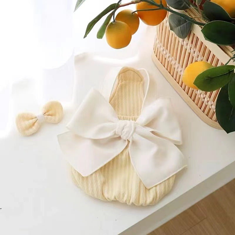 Salopette d'été pour chien jaune avec nœud et accessoire assorti, décorée sur une table ensoleillée.
