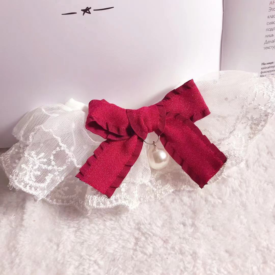Bavoir en dentelle avec un nœud rouge et perle, idéal pour chien et chat, élégant et pratique pour animaux de compagnie.