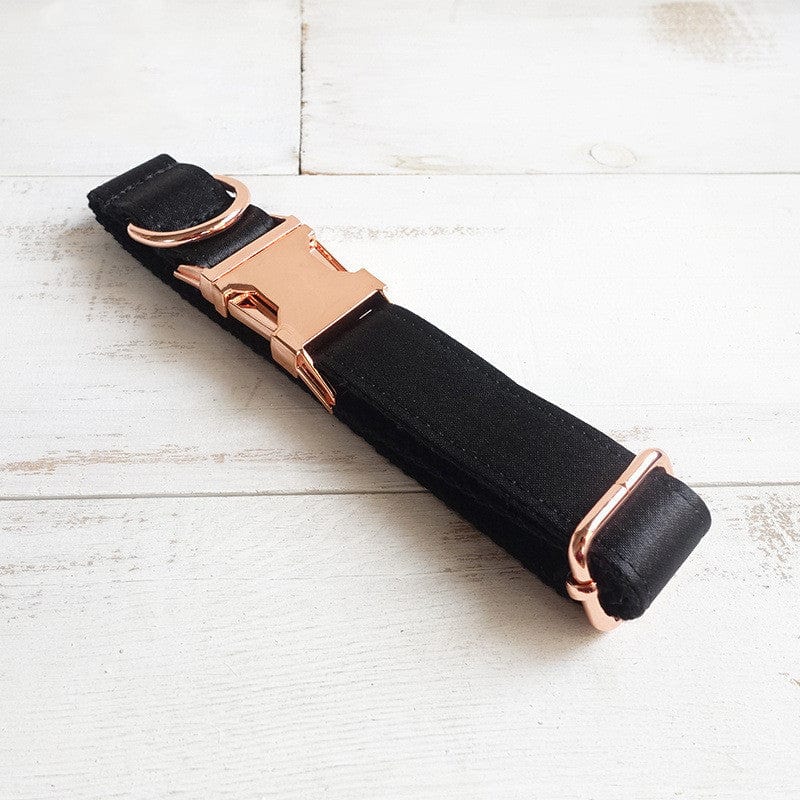 Collier pour chien noir en polyester avec boucle en métal rose sur fond clair.