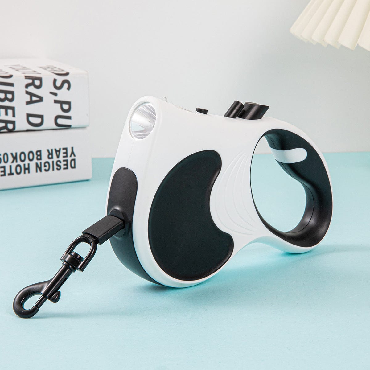Laisse automatique rétractable pour animaux avec lumière intégrée en coloris blanc et noir.