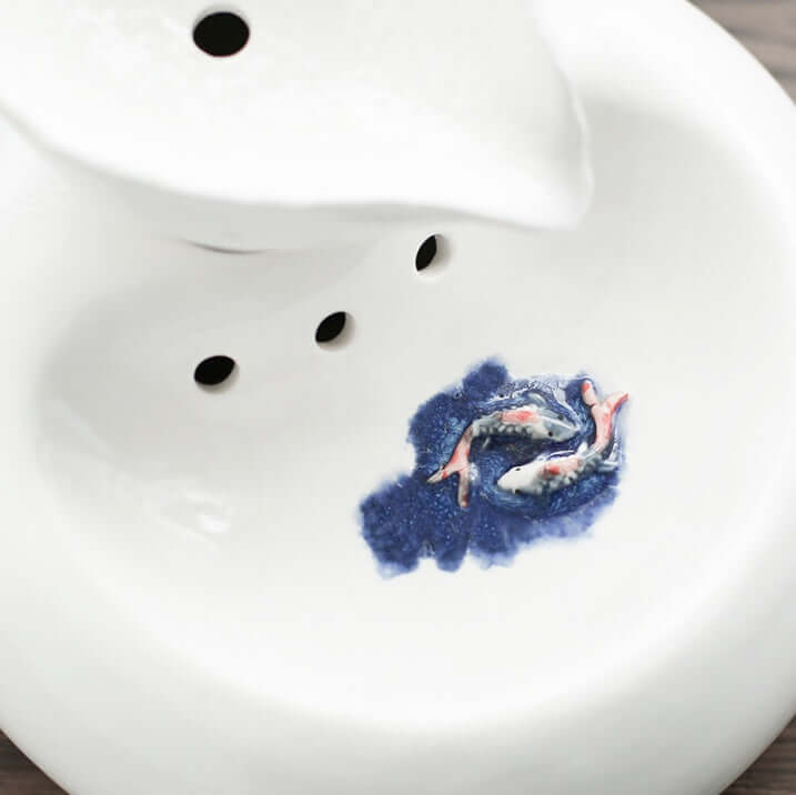 Distributeur d'eau automatique en porcelaine pour chat avec motif de poissons colorés.
