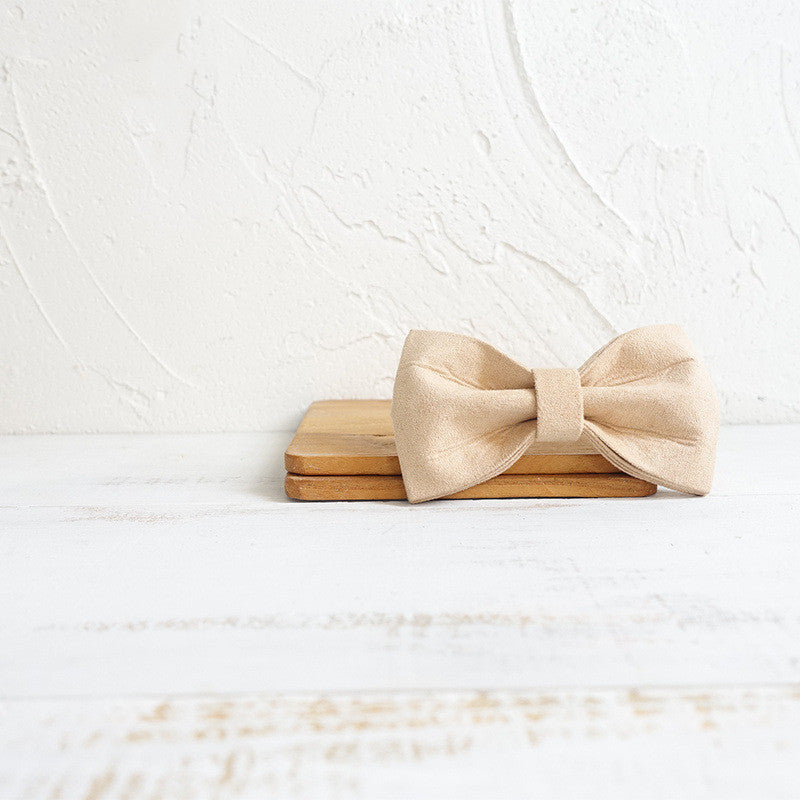 Nœud papillon en polyester fait main pour chien, couleur beige, sur un support en bois.
