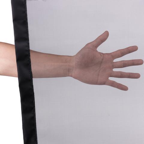 Main de personne à travers une barrière de séparation portable en maille pour animaux, mettant en avant sa transparence.