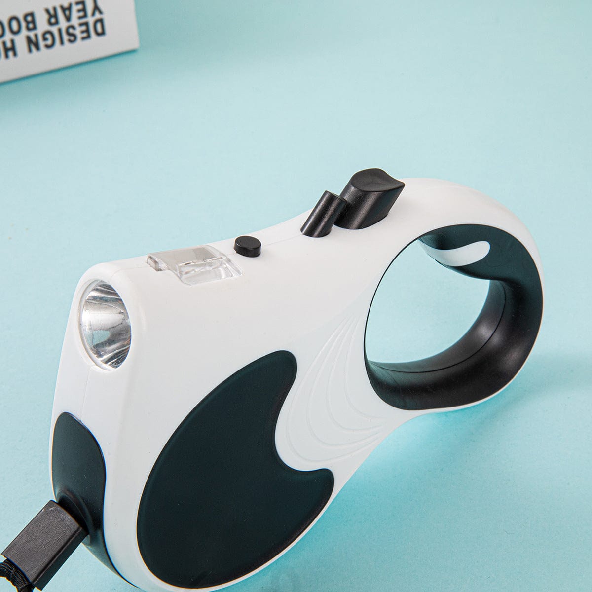 Laisse automatique rétractable pour animaux avec lumière, couleur blanche et noire, idéale pour promenades nocturnes.