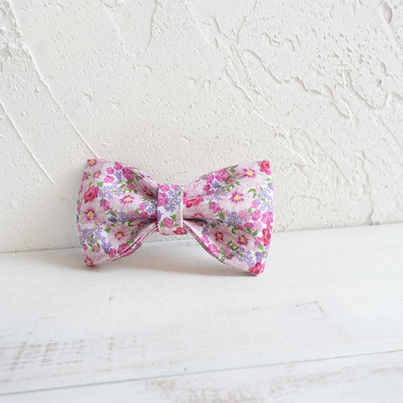 Nœud papillon en polyester à fleurs pour chien sur fond blanc, accessoire élégant pour animaux.