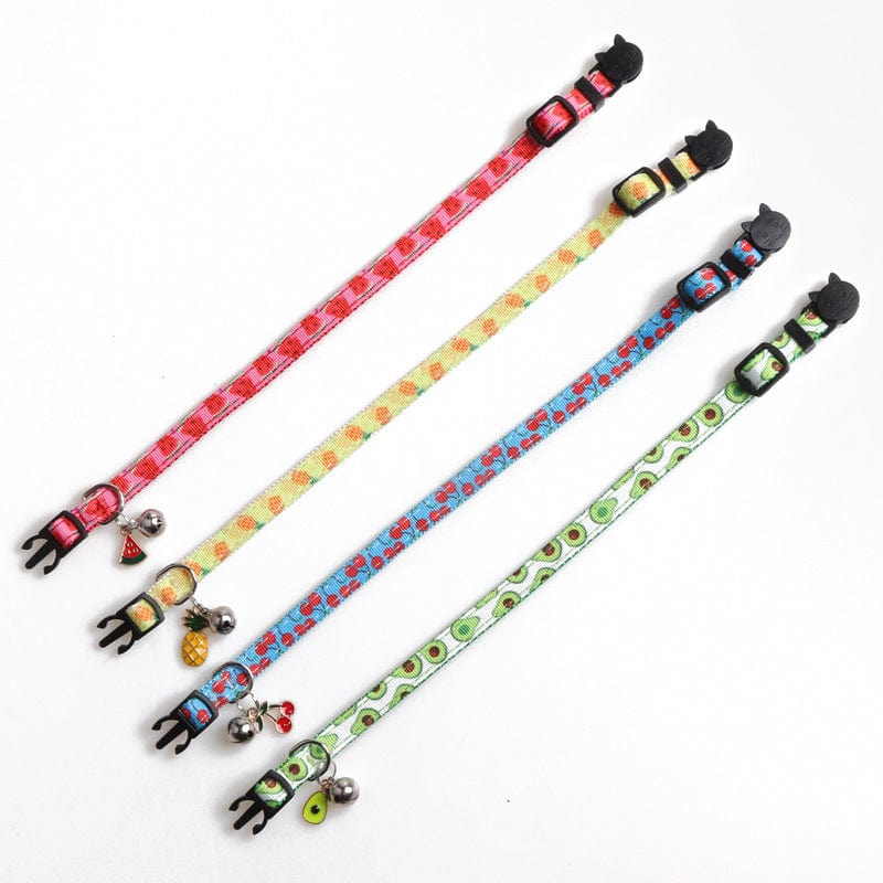 Colorful fruit-patterned cat collars with bells, featuring red, yellow, blue, and green designs.