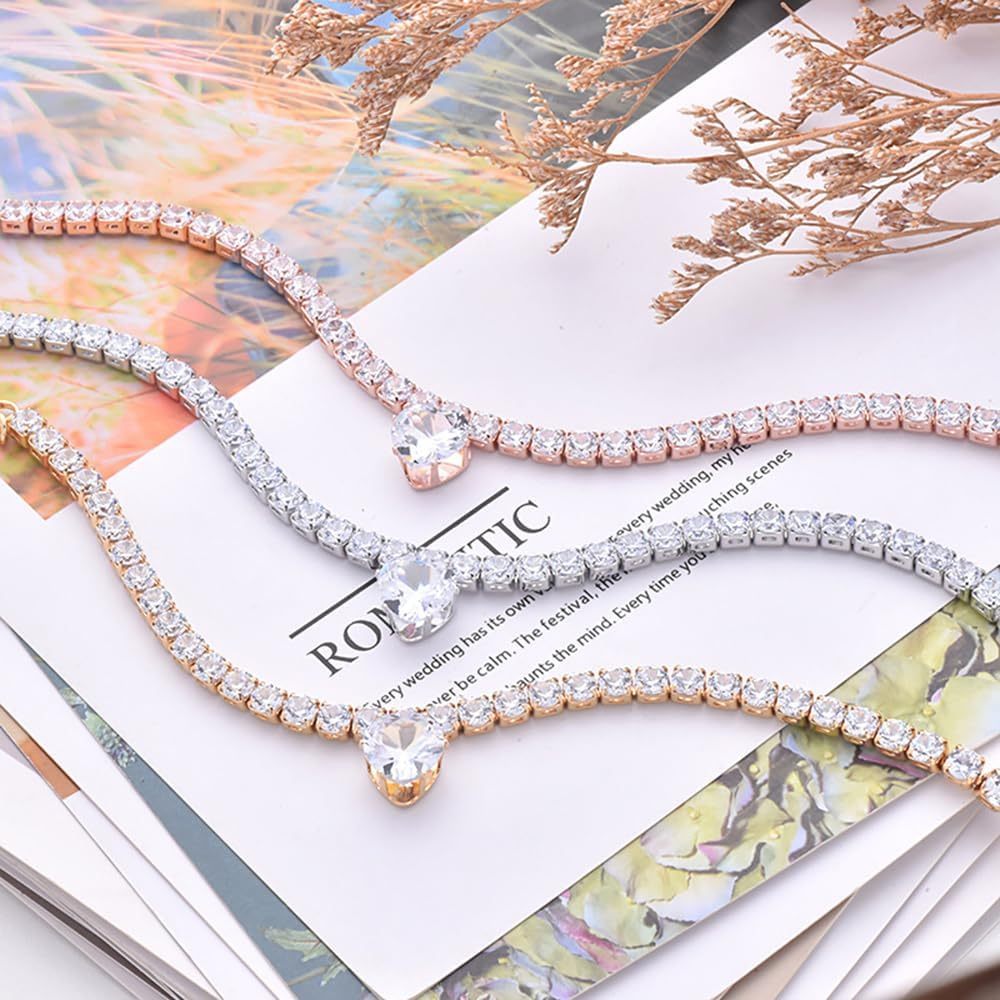 Collier en rhinestones en forme de cœur pour animaux, disponible en plusieurs couleurs, posé sur des magazines.