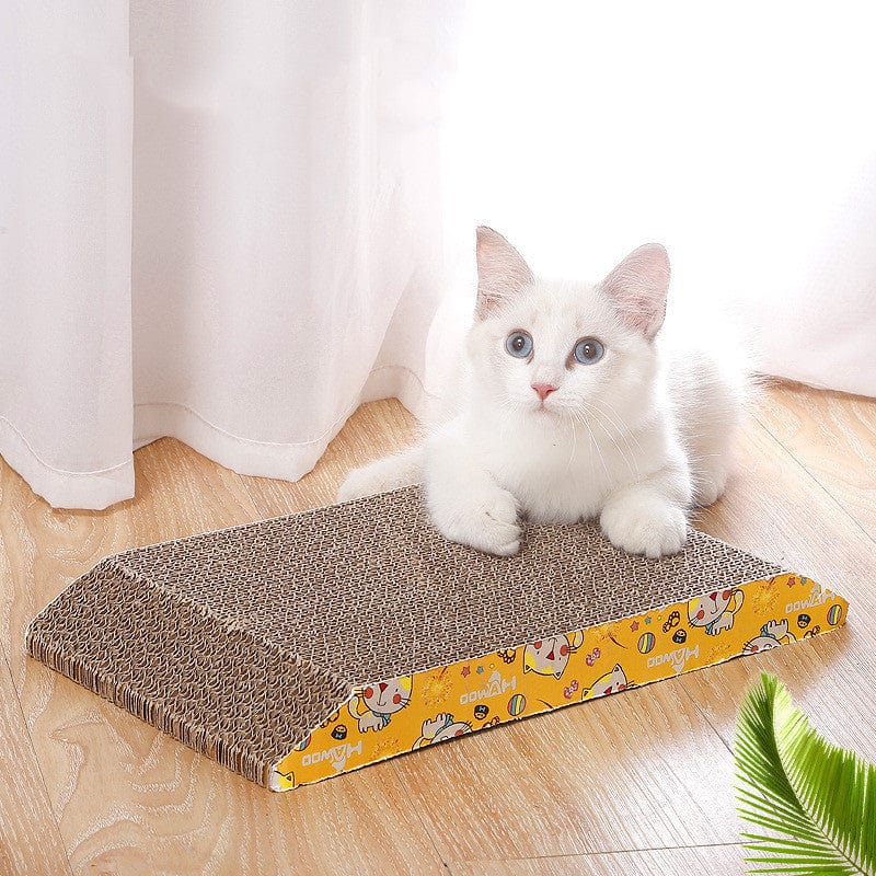 Chat blanc reposant sur une planche à gratter en carton ondulé trapézoïdal dans un intérieur lumineux.