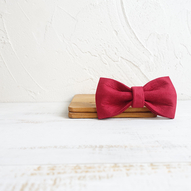 Élégant nœud en satin rouge posé sur un support en bois, parfait pour accessoiriser un collier pour chien.