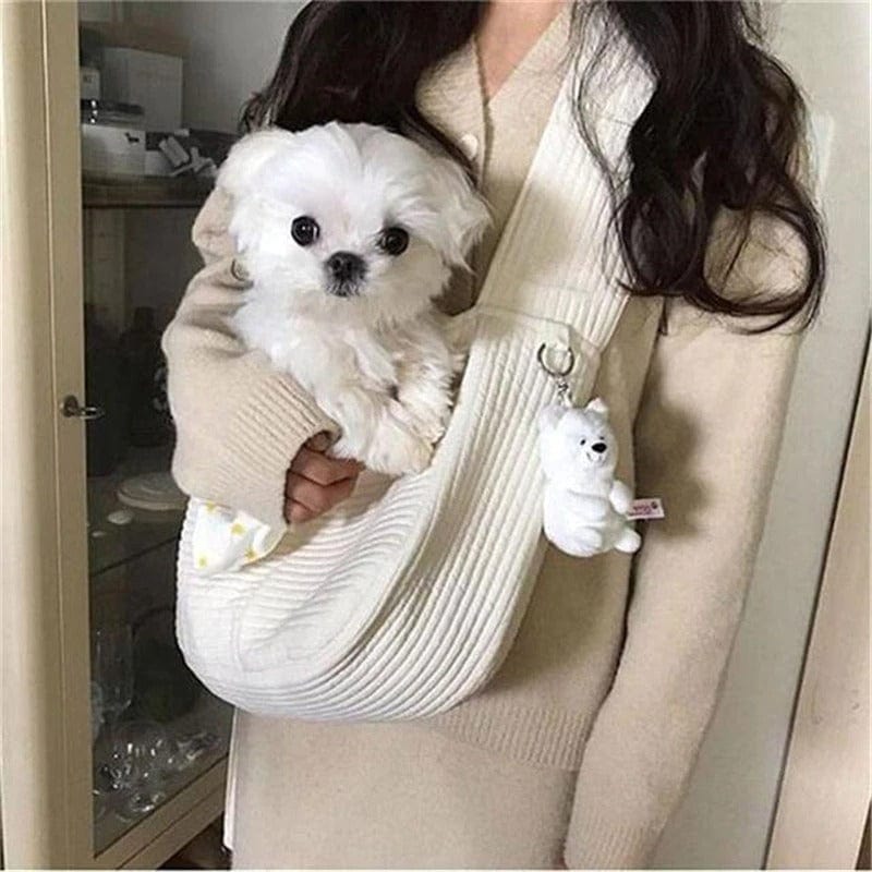 Sac de transport blanc pour petits chiens, porté par une personne avec un chien blanc à l'intérieur.