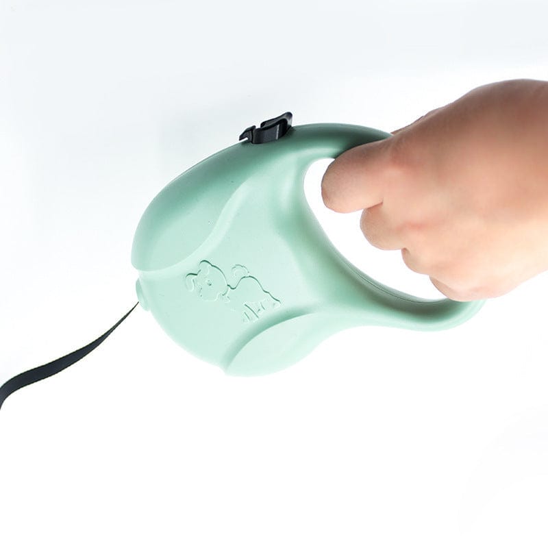 Main handle of a green automatic retractable dog leash with a hand holding it.