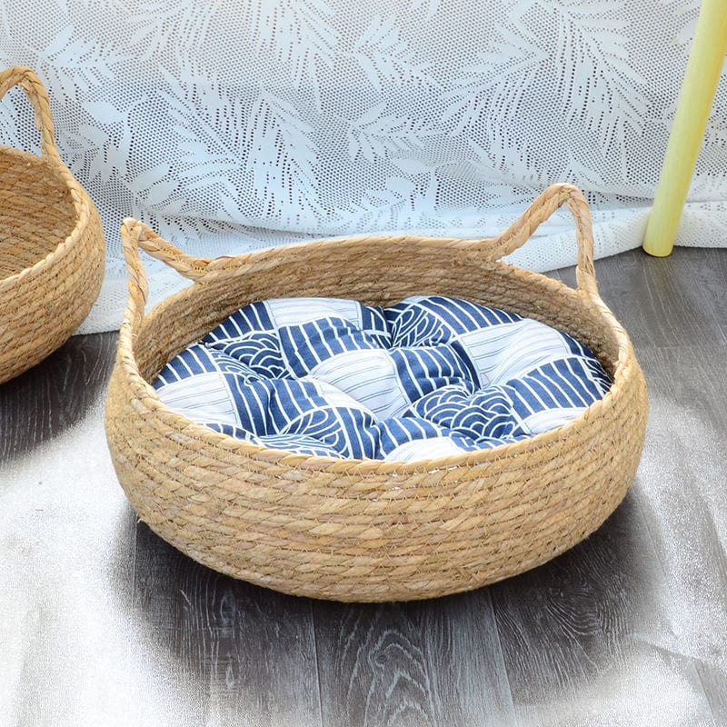 Panier confortable en rattan décoré, idéal pour animaux de compagnie, avec coussin en tissu à motifs bleus.