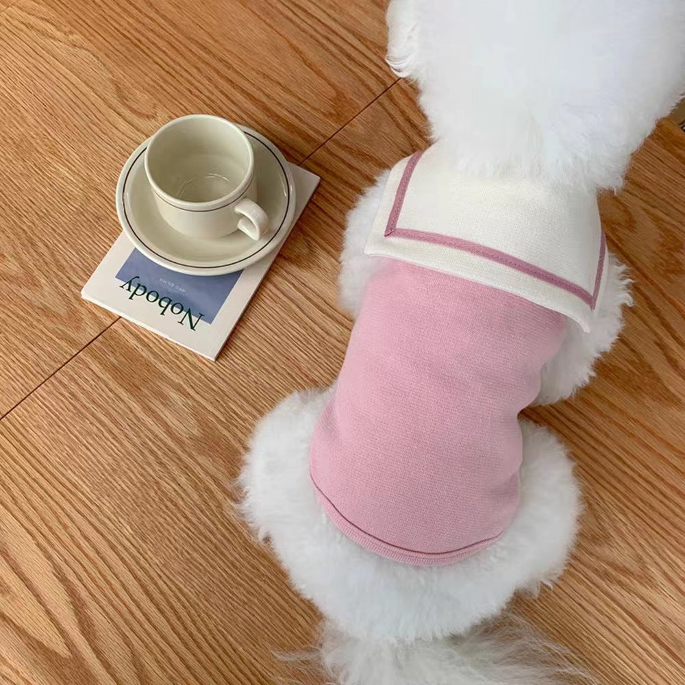 Gilet marin rose pour petits animaux avec col sailor, posé à côté d'une tasse sur une table en bois.