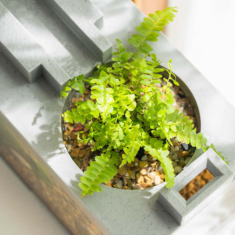 Plante verte dans un pot de décoration moderne avec gravier et design géométrique en béton.