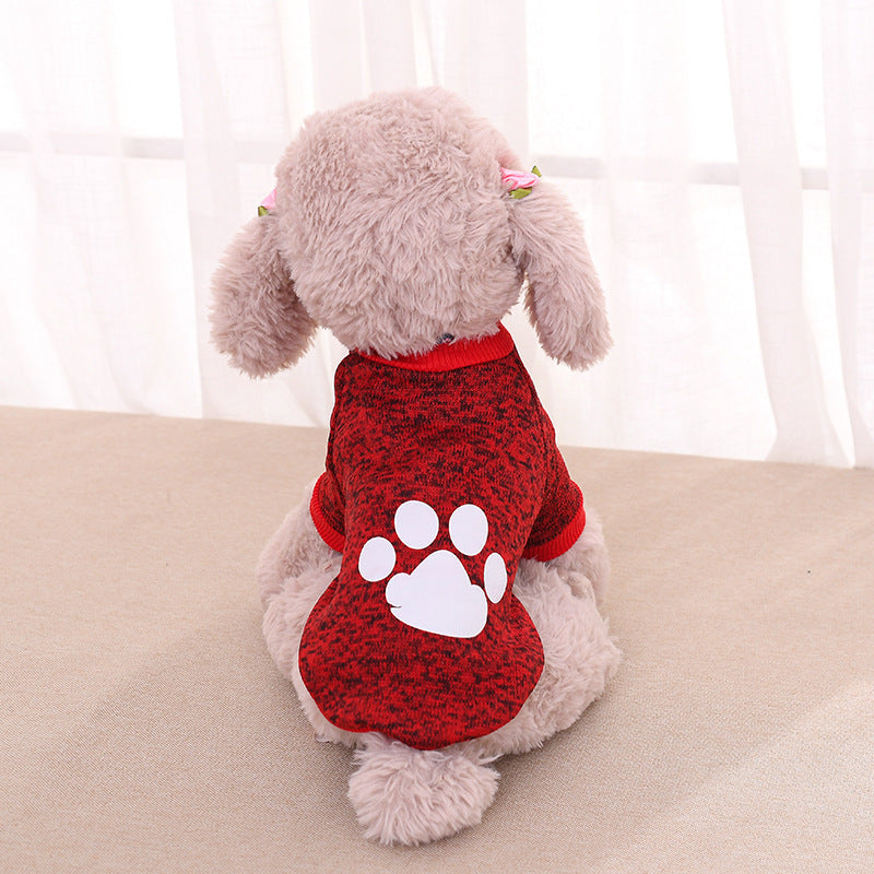 Chien en peluche portant un pull en laine rouge avec motif de patte, style décontracté.