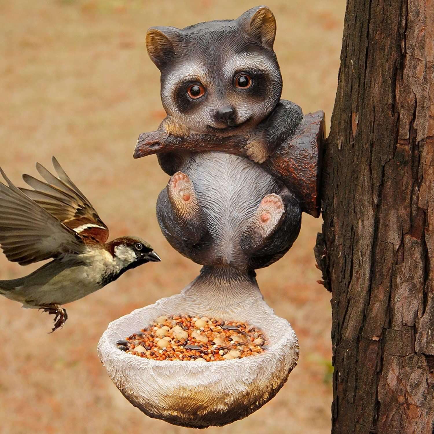 Mangeoire à oiseaux en résine en forme de raton laveur, avec un oiseau attendant de se nourrir.