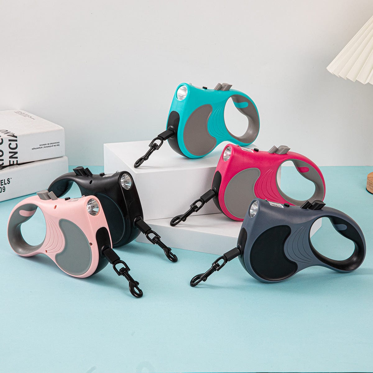 Laisse automatique rétractable pour animaux en plusieurs couleurs avec lumière intégrée pour sécurité nocturne.