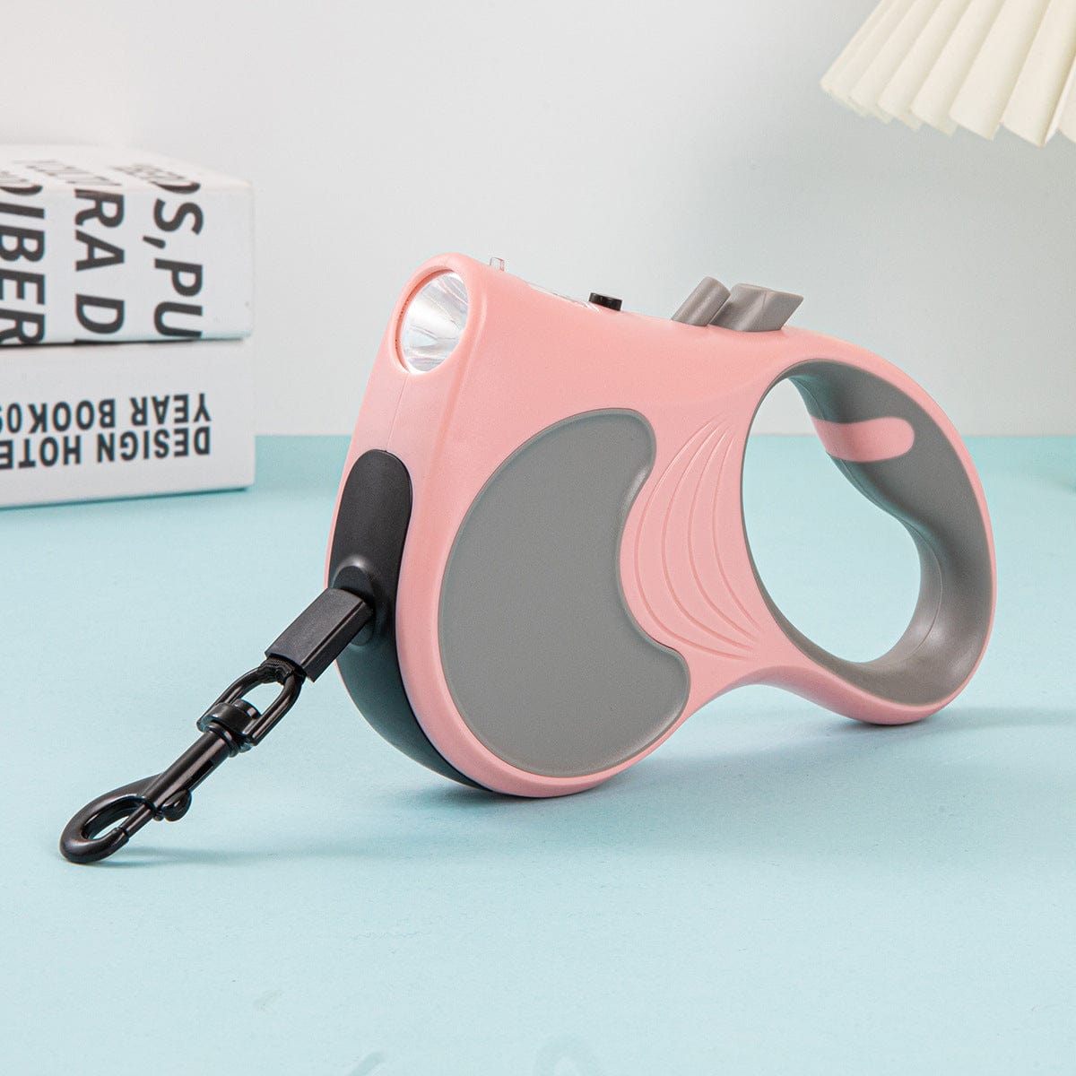 Laisse automatique rétractable pour animaux de compagnie en coloris rose, avec lumière intégrée pour visibilité nocturne.