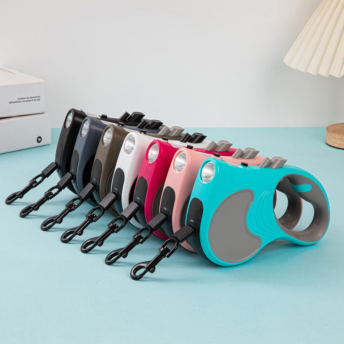 Laisse automatique rétractable multicolore avec lumière intégrée pour chiens, vue sur plusieurs couleurs disponibles.