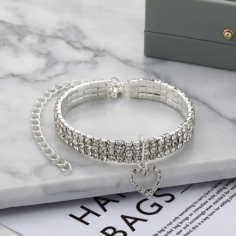 Collier en strass à trois rangées pour animaux, élégant et chic, avec un pendentif en cœur, sur marbre.