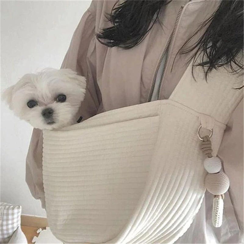 Femme portant un sac de transport blanc avec un petit chien à l'intérieur, idéal pour les voyages.